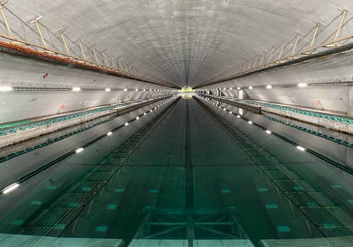 コンクリートに囲まれた、長い実験用水槽。左右に照明とレールが等間隔に並んでいる