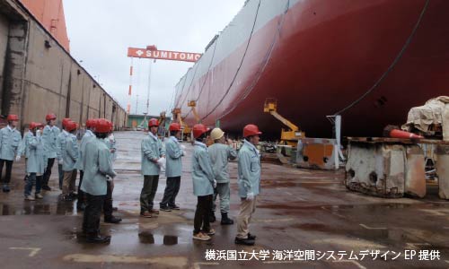 施設で地図を広げて係員の説明を聞く子ども達の学習風景